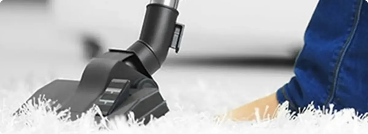 Close-up of a professional vacuuming a white carpet in Converse.